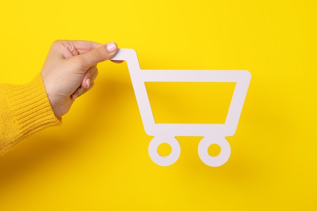 Premium Photo | The shopping cart in female hand over yellow background