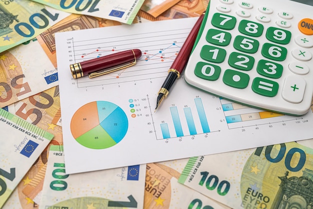 Premium Photo | Banknotes of 50 euros are scattered and on them a graph calculator pen Business concept