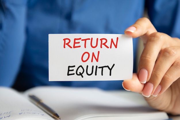 Premium Photo | Return on equity is written on a white business card in a woman's hand. Blue background. Business and advertising concept