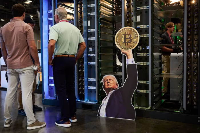 Hình ảnh Tổng thống Hoa Kỳ Donald Trump cầm một token Bitcoin tại gian hàng Moonshots trong hội nghị Bitcoin 2025